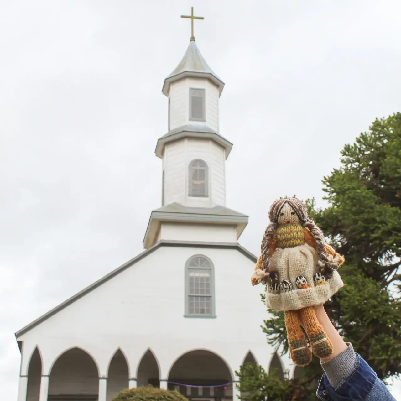 Muñeca Panchita frente a una iglesia de Chiloé.