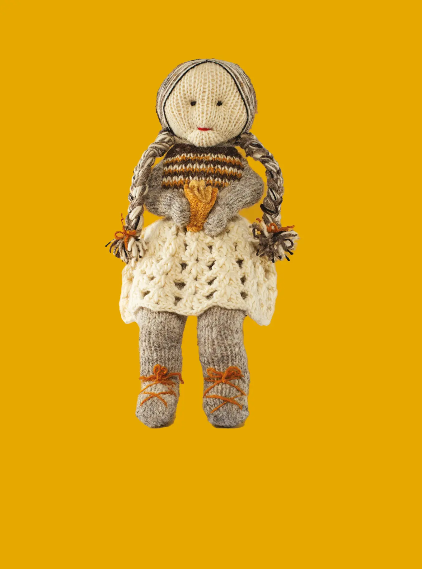 Muñeca de lana que representa a una abuela sobre fondo amarillo.