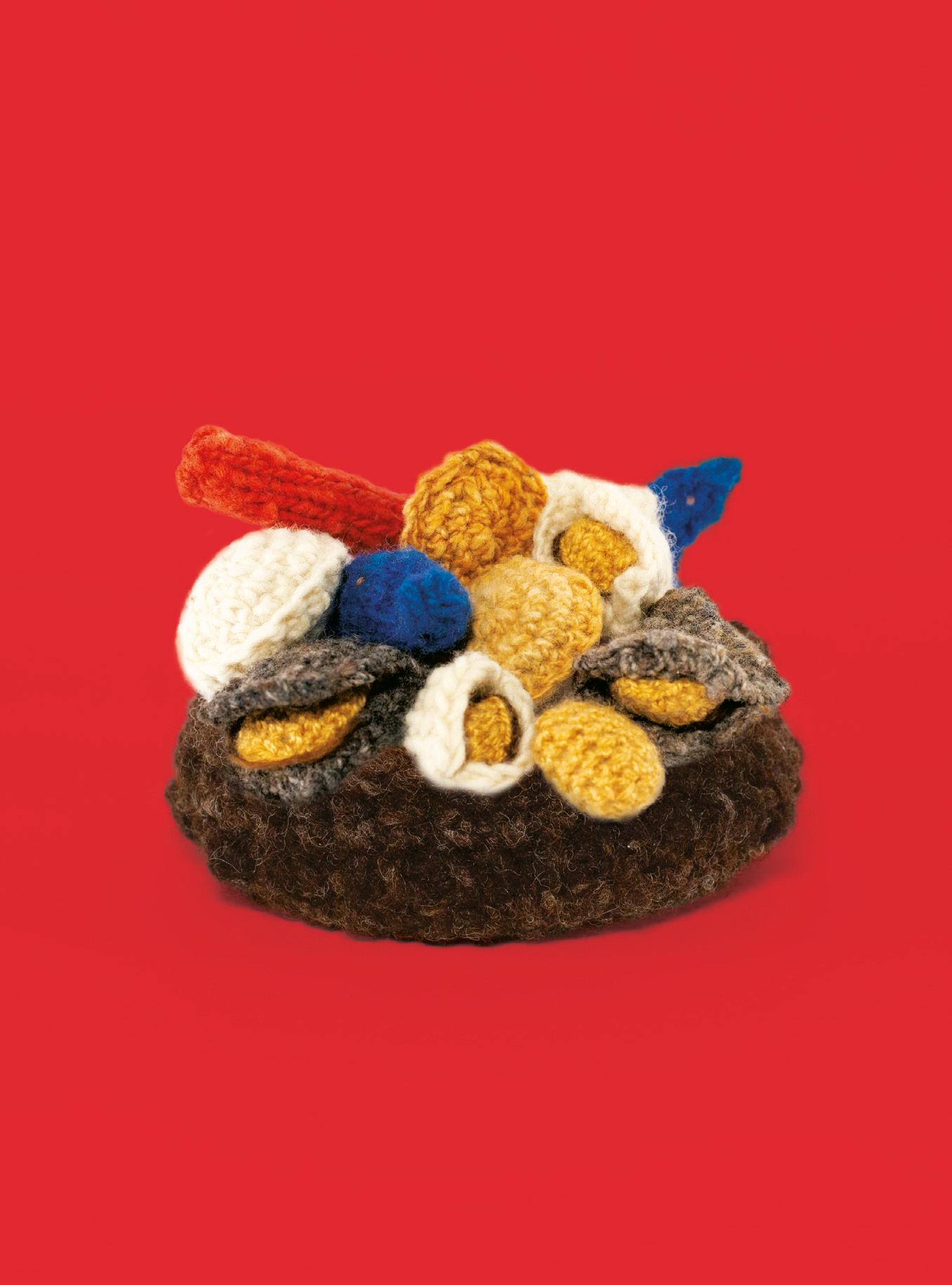 Muñecos de lana que representan a un curanto sobre fondo rojo.