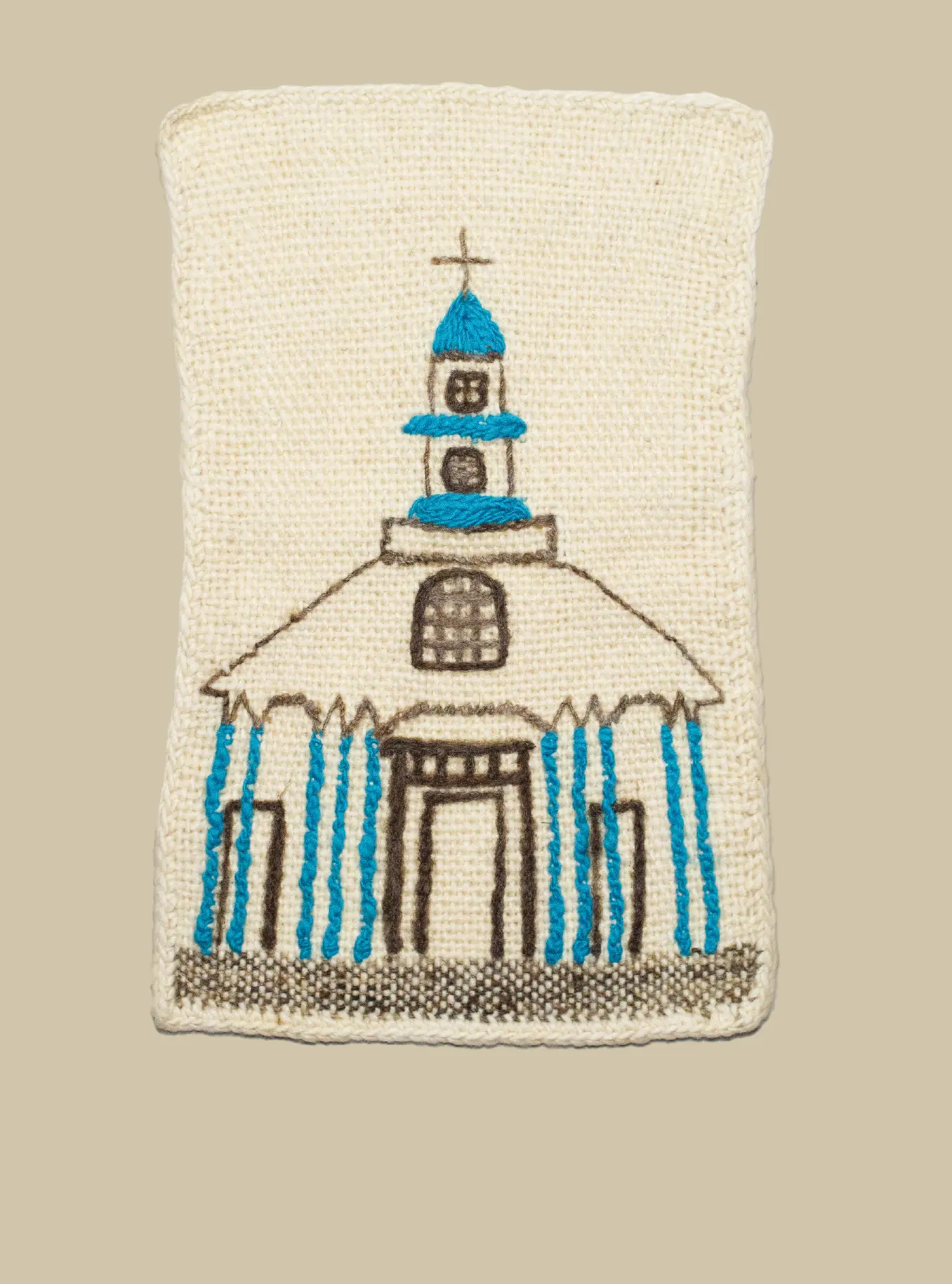 Tapiz de lana con imagen de una iglesia chilota bordada.