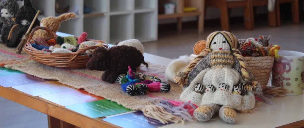 Muñecos de lana tejidos por artesanas dalcahuinas expuestos sobre una mesa.