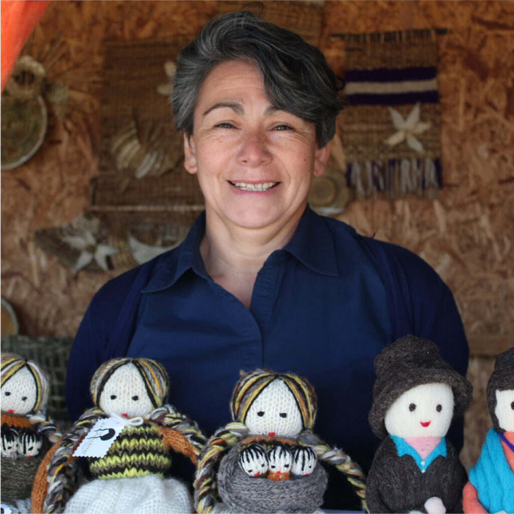 Artesana Dalcahuina Malvina García posa junto a muñecos tejidos con lana.