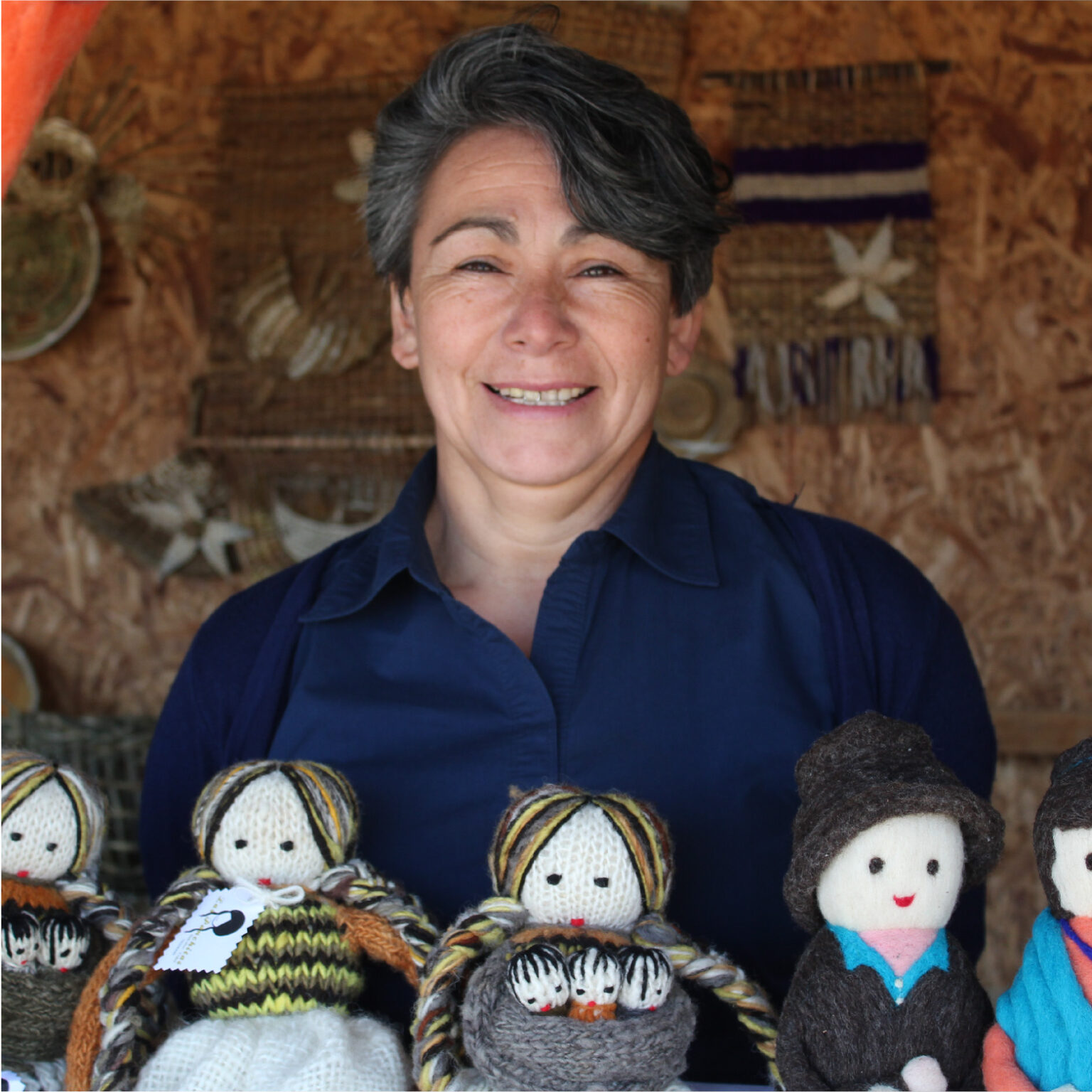 Artesana Dalcahuina Malvina García posa junto a muñecos tejidos con lana