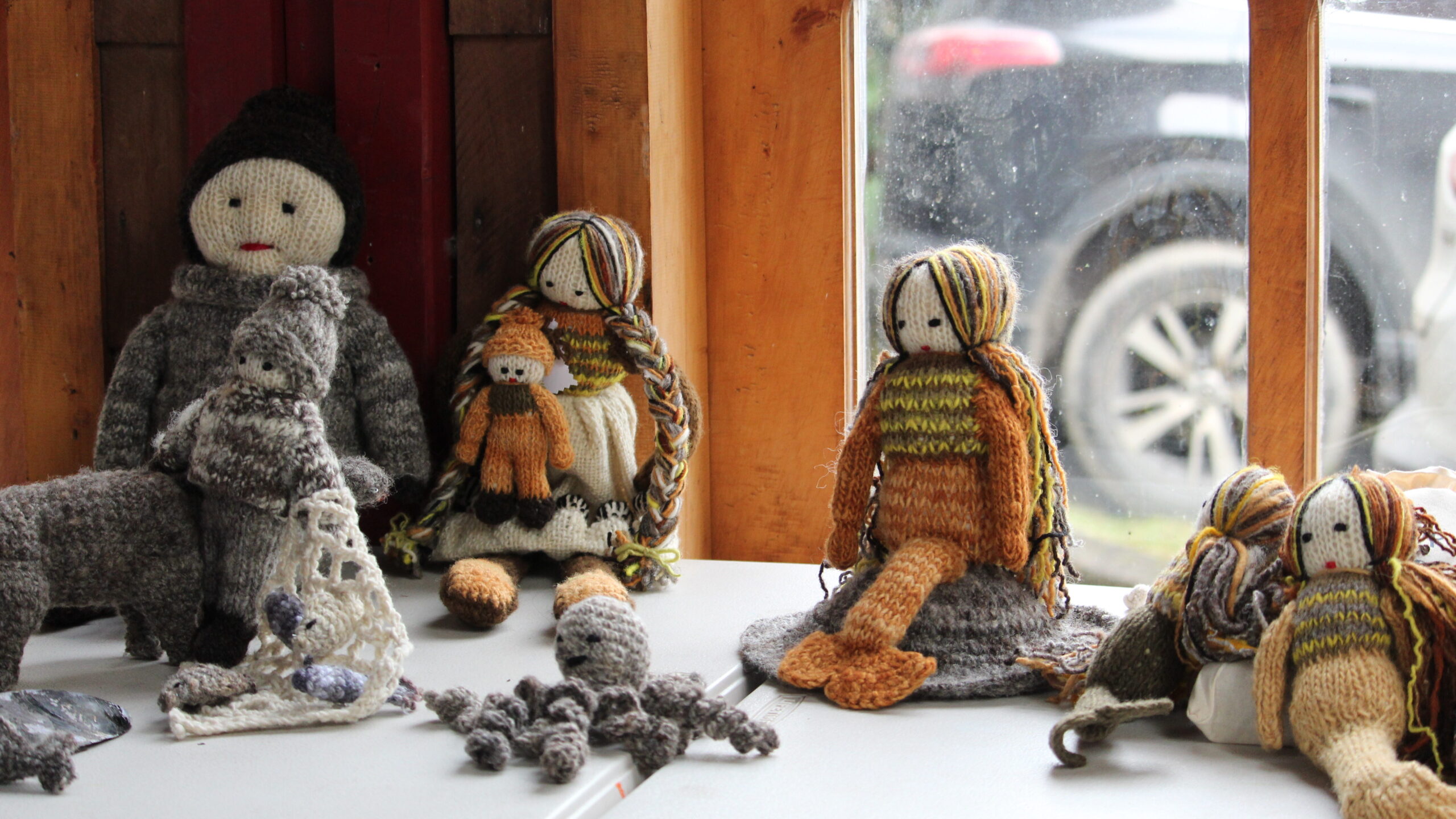 Muñecos de lana tejidos por la artesana dalcahuinas Malvina García expuestos sobre una mesa. 